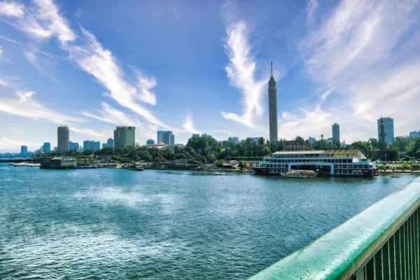 Cairo skyline with Nile River, Cairo Tower, and modern riverfront buildings.